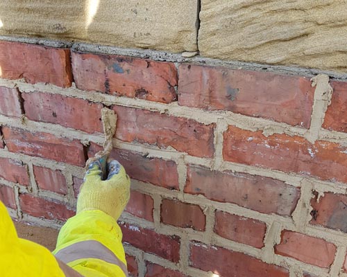bricklayer pointing a brick wall with lime mortar